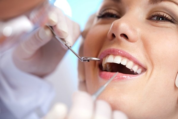 pacjent w trakcie badania jamy ustnej, stomatolog wykonuje sanację jamy ustnej